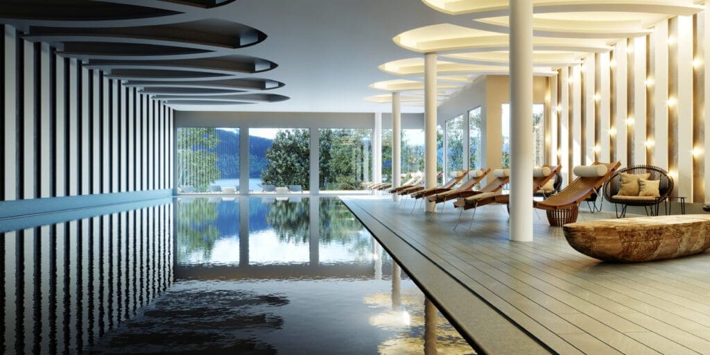 Modern indoor swimming pool with lounge chairs, large windows showing trees and a lake, wooden accents, and unique ceiling lights.