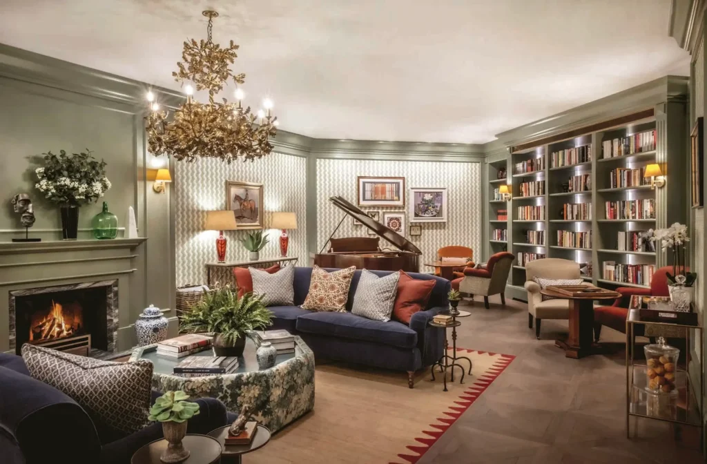 Elegant living room with fireplace, grand piano, bookshelves, sofas, and decorative lighting; various plants and art pieces accent the cosy space—perfect for relaxing or learning about Programmatic Display in a stylish, well-lit setting.